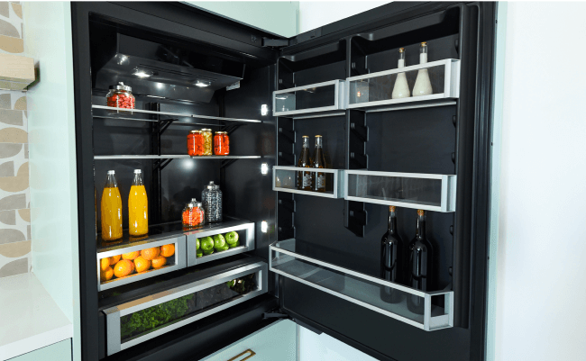 L'intérieur d’un réfrigérateur JennAir éclairé, contenant des boissons et des condiments.  L'intérieur d’un réfrigérateur JennAir éclairé, contenant des boissons et des condiments.